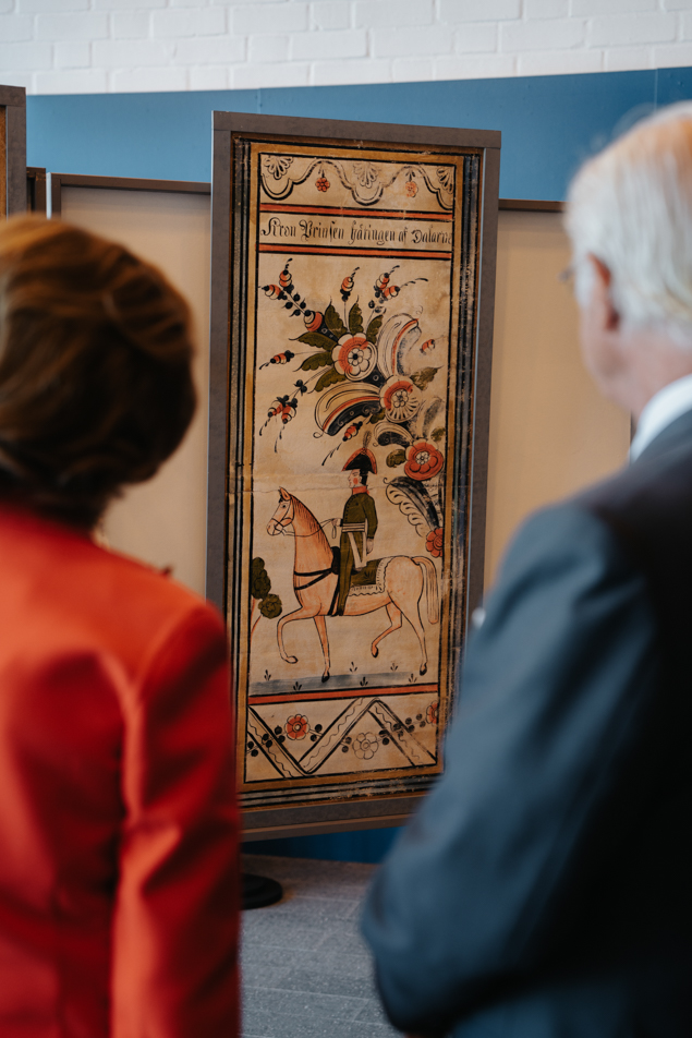 Kungen och Drottningen vid en dalmålning som avbildar den första Bernadottens ankomst till Sverige.